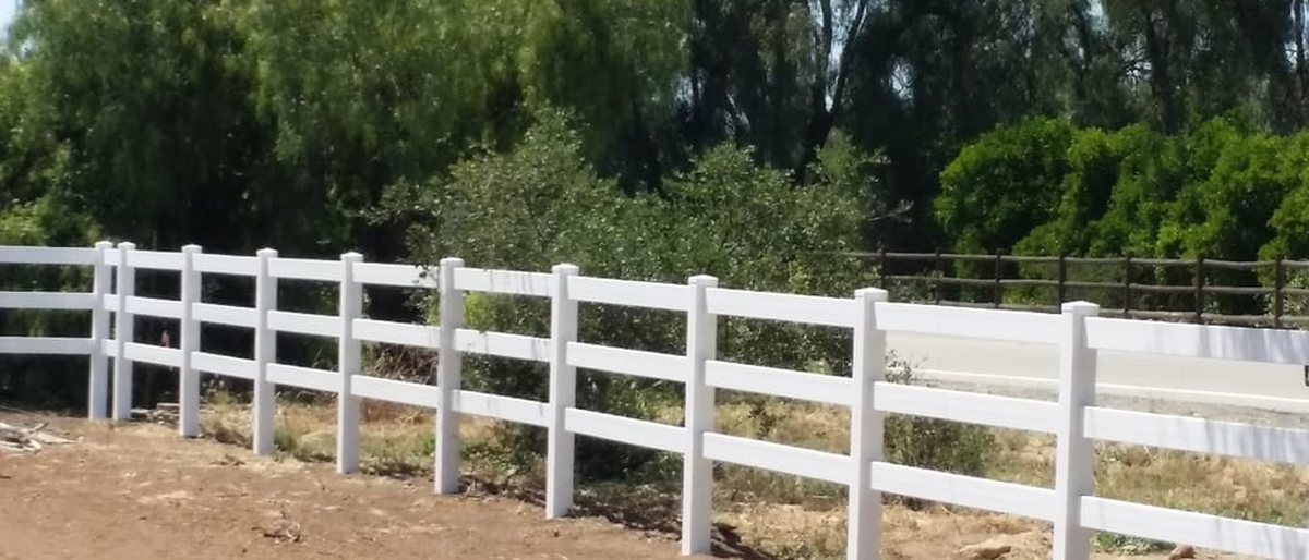 White three-rail ranch fence running along a rural property built by Valley Center Fence Co. in Valley Center, California