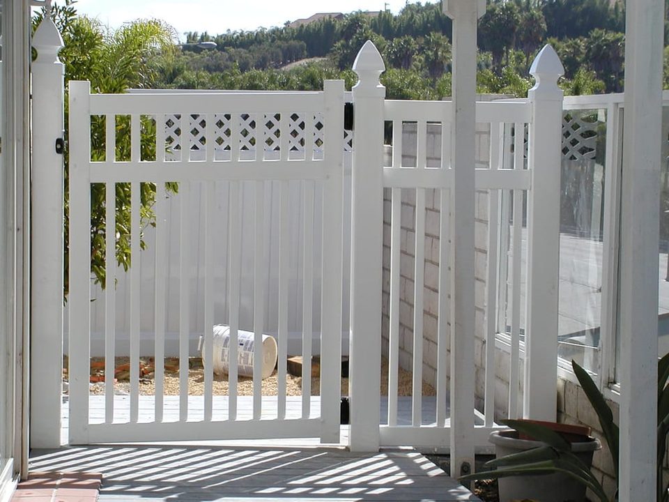 White vinyl gate with scalloped picket top and matching fence panels