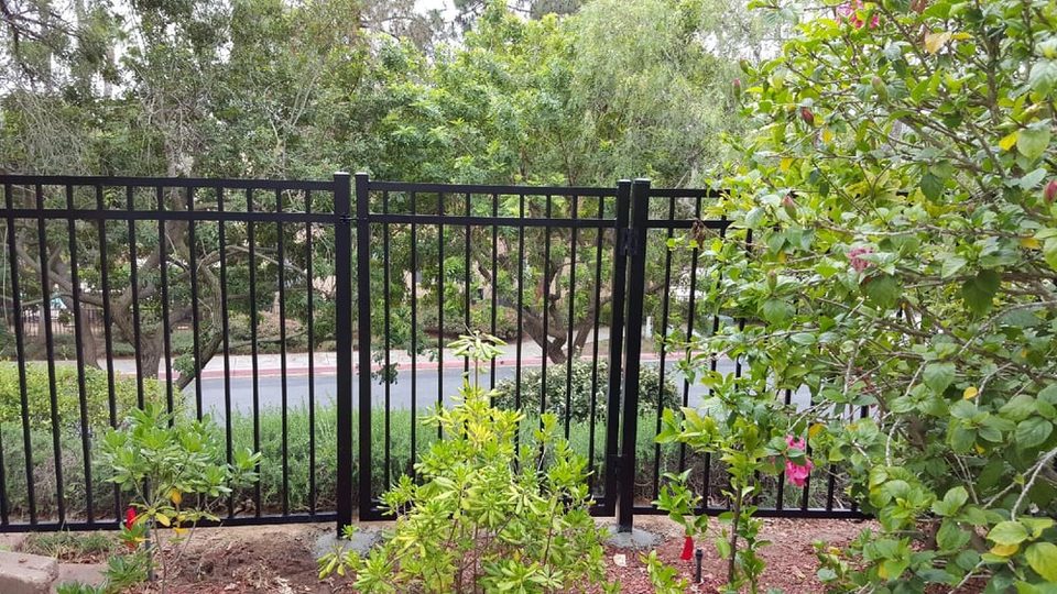 Custom iron gate set into an ornamental iron fence